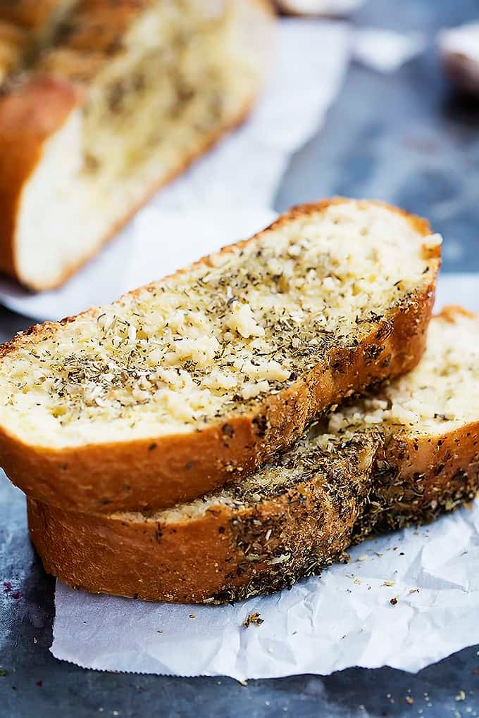 two slices of grilled garlic bread stacked on top of each other with the rest of the loaf in the background.