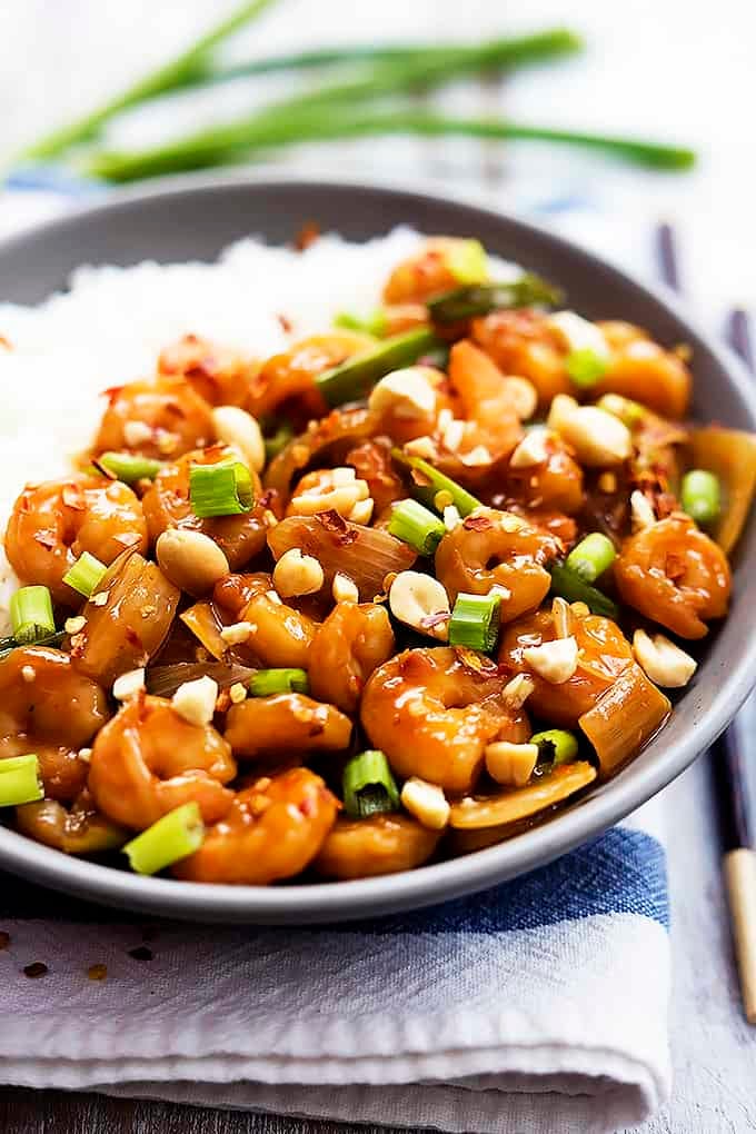 kung pao shrimp with rice on a plate with chopsticks on the side.