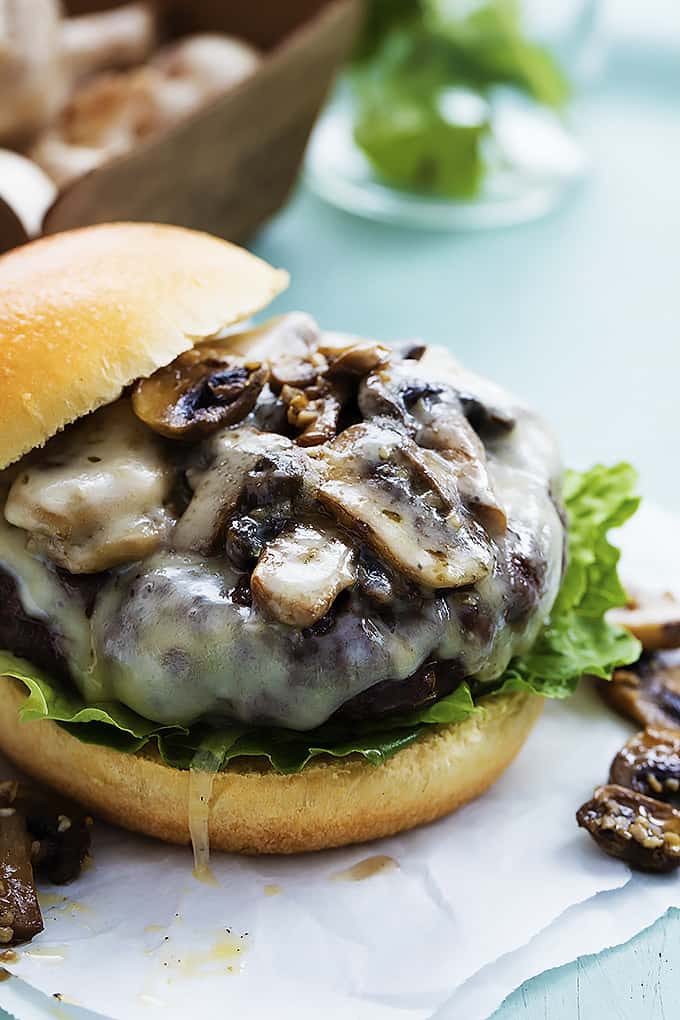 a mushroom swiss burger with the top slide off on the side.