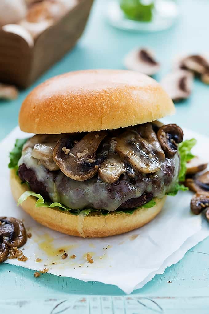 a mushroom swiss burger with mushrooms around it.