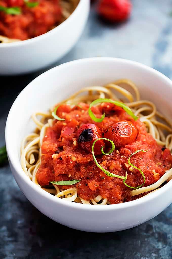 fire roasted tomato pasta sauce and pasta in a bowl with another bowl of pasta and sauce in the background.