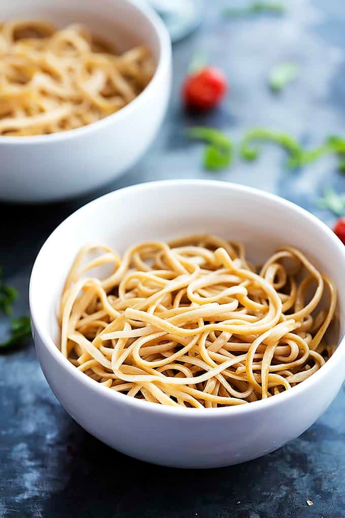 a bowl of pasta with another bowl of pasta in the background.