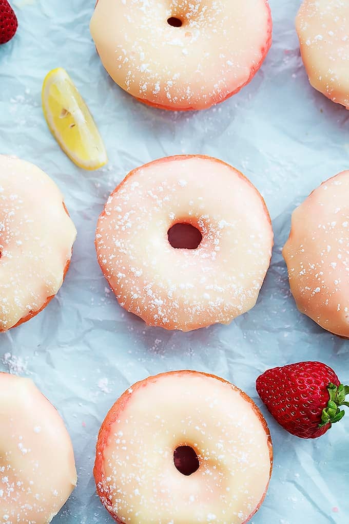 top view of strawberry lemonade donuts with a strawberry and a lemon slice on the side.