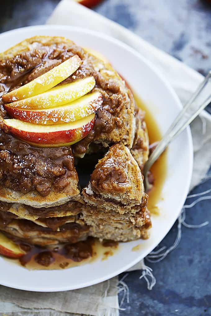 top view of a stack of apple cinnamon streusel pancakes on a plate with a chunk separated from the rest of the stack sitting on a fork.