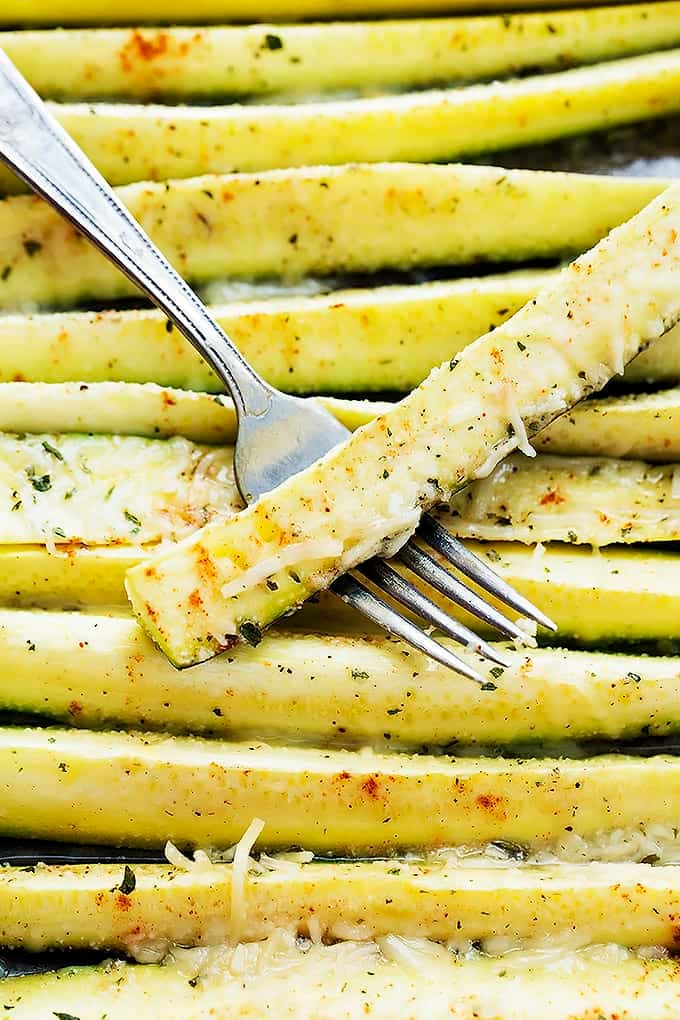 top view of baked cheesy ranch zucchini with a fork holding a baked cheesy ranch zucchini on top of them.