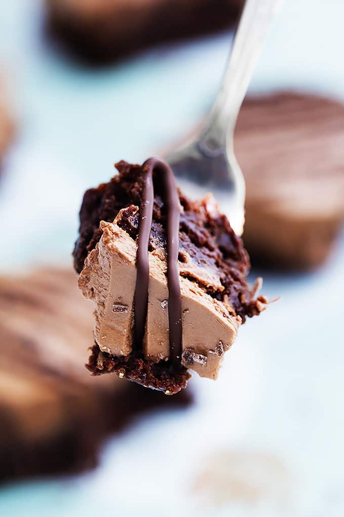 close up of a bite of a chocolate mousse brownie on a fork with more brownies faded in the background.