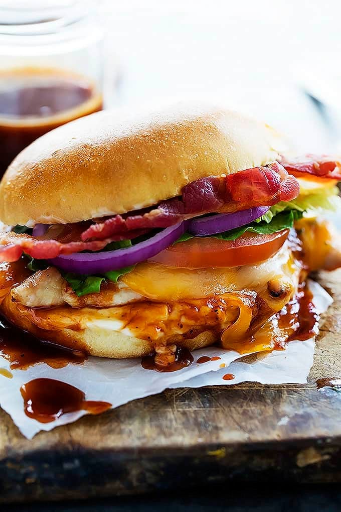 close up of a monterey chicken sandwich with a jar of sauce in the background.