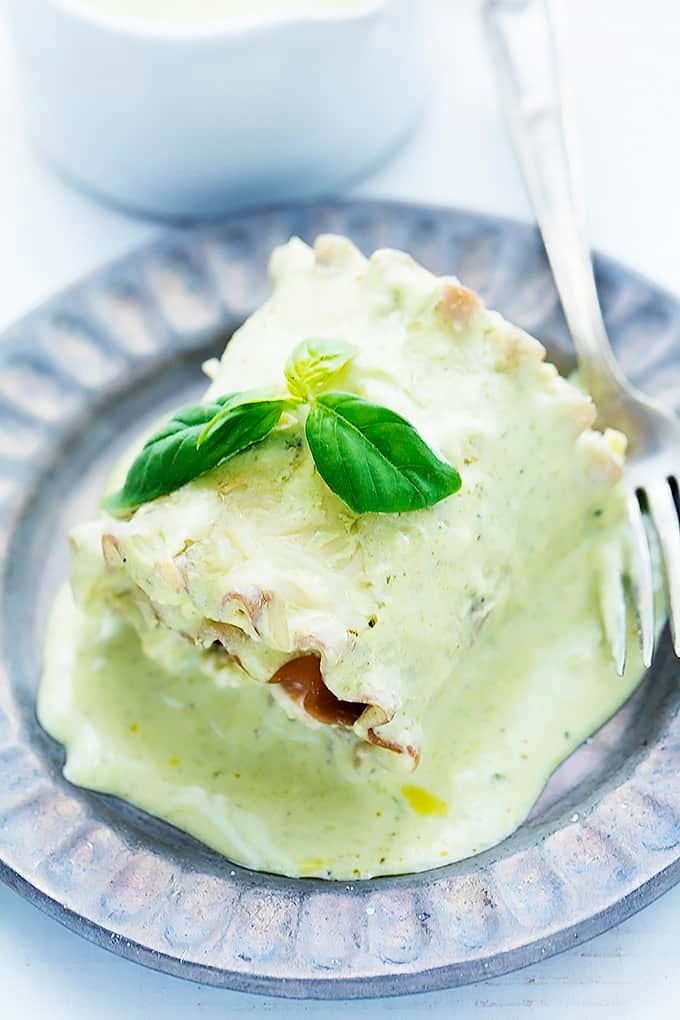 a creamy pesto chicken lasagna roll with a fork on a plate.