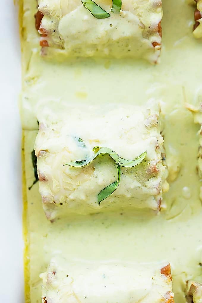close up top view of creamy pesto chicken lasagna rolls in a cooking tray.