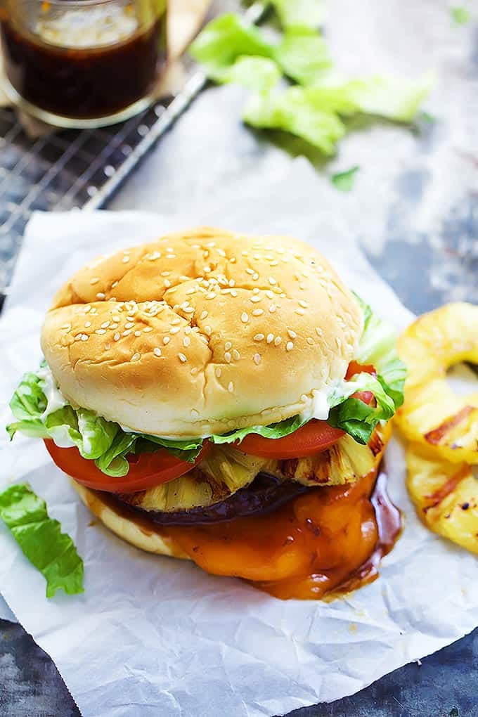 a Red Robin bonzai burger with pineapple slices on the side and a jar of sauce in the background.