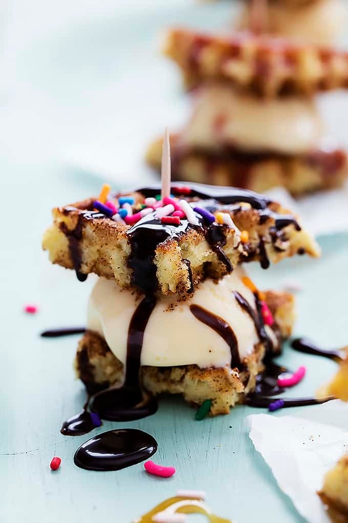 a snickerdoodle waffle ice cream sandwich topped with chocolate syrup, sprinkles and a toothpick.