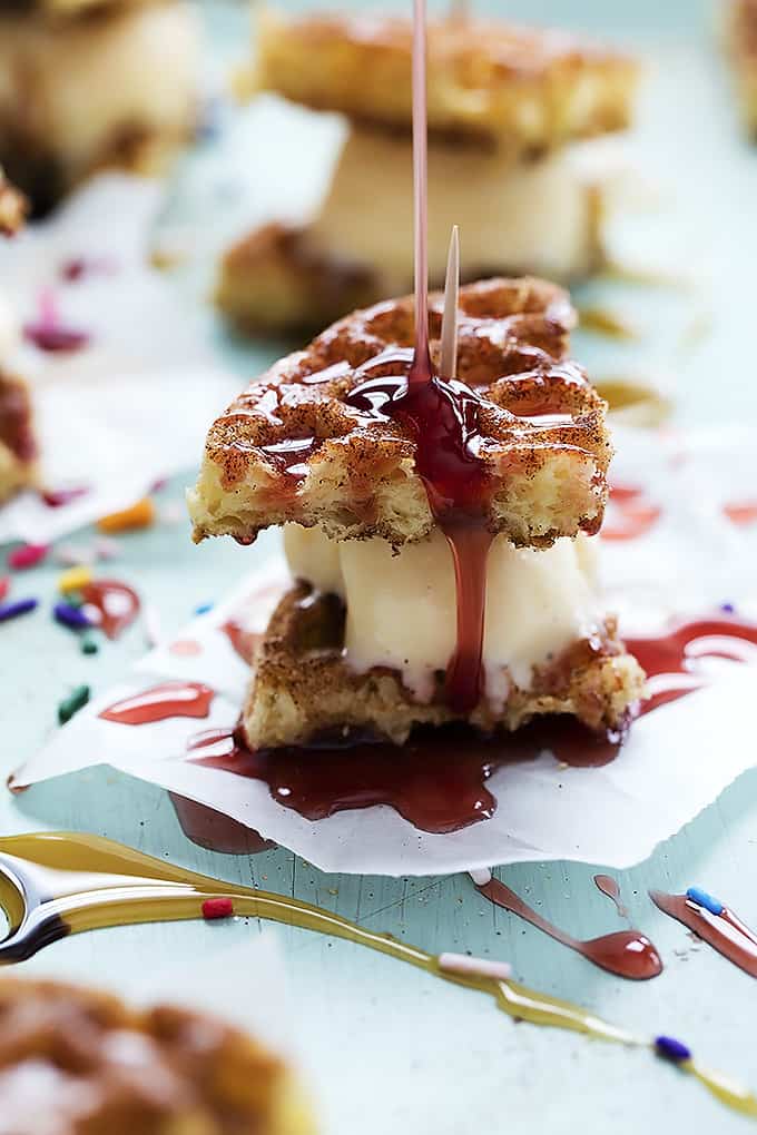a snickerdoodle waffle ice cream sandwich with strawberry sauce being poured on top.
