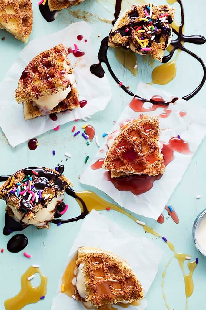 top view of snickerdoodle waffle ice cream sandwiches with either caramel, strawberry, raspberry or chocolate sauce on top.