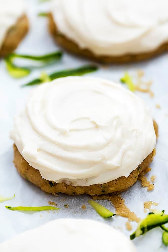 a zucchini cookie with brown butter cream cheese frosting with more cookies in the background.