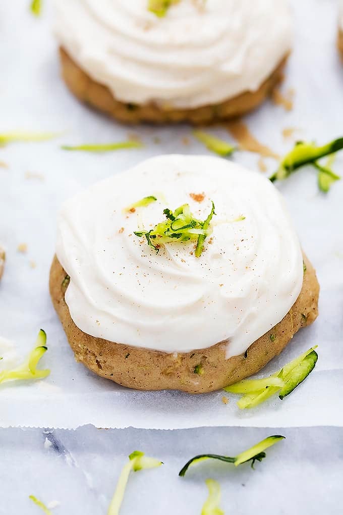 a zucchini cookie with brown butter cream cheese frosting with another cookie in the background.