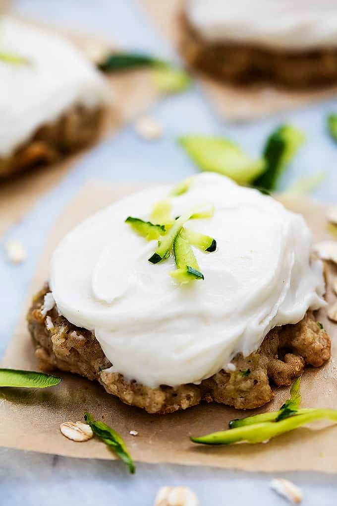 a frosted zucchini oatmeal cookie with more cookies in the background.