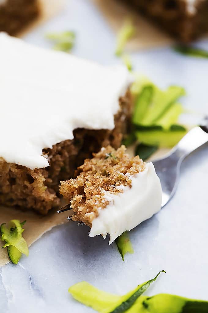 a piece of zucchini sheet cake with a bite of it on a fork in the front.