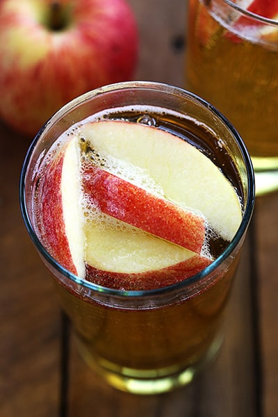 sparkling apple cider in a glass with apples on top.