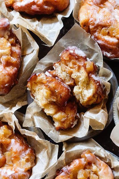 close up top view of glazed apple fritters in a muffin tin.