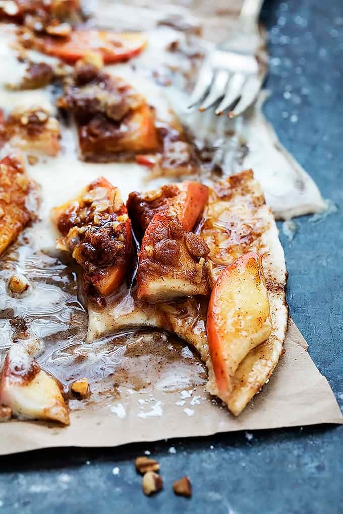 close up of a piece of apple crumble flatbread with bites missing and a fork in the background.