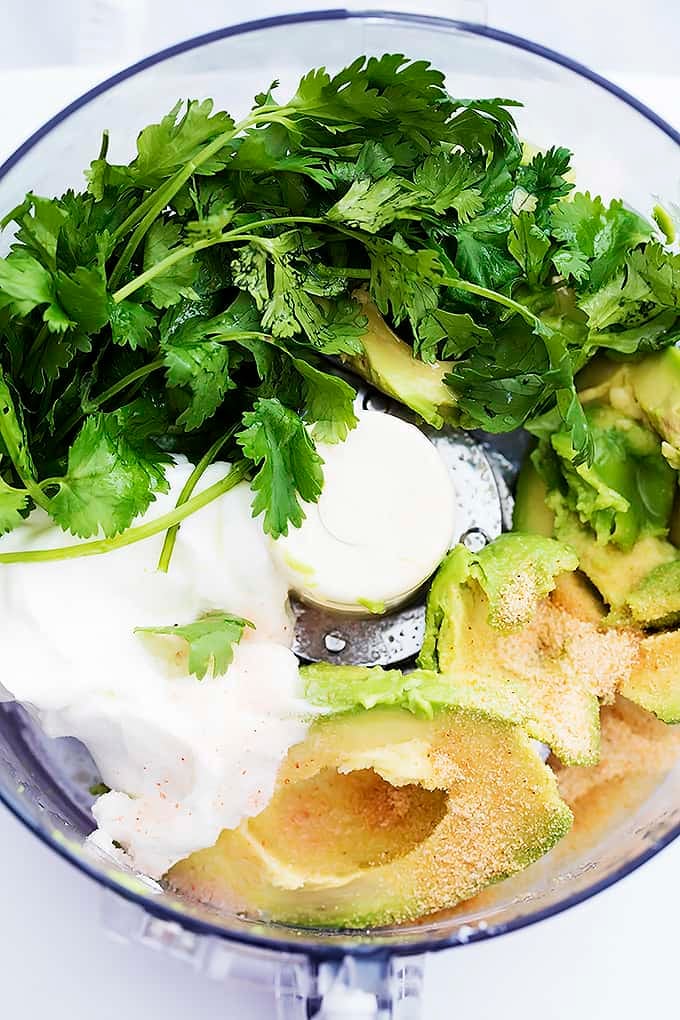 close up top view of zesty avocado sauce ingredients unmixed in a blender.