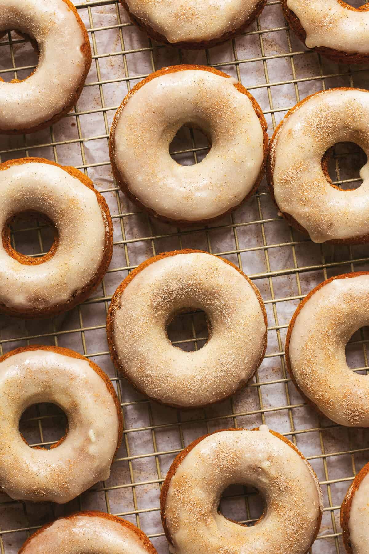Overhead of baked pumpkin donuts on a cooling rack.