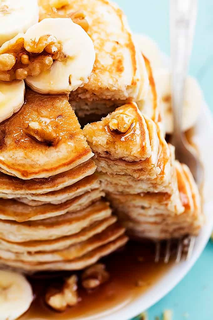 close up of a stack of banana bread pancakes with a bite sitting on a fork.
