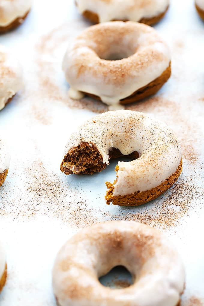 baked pumpkin donuts with one missing a bite.