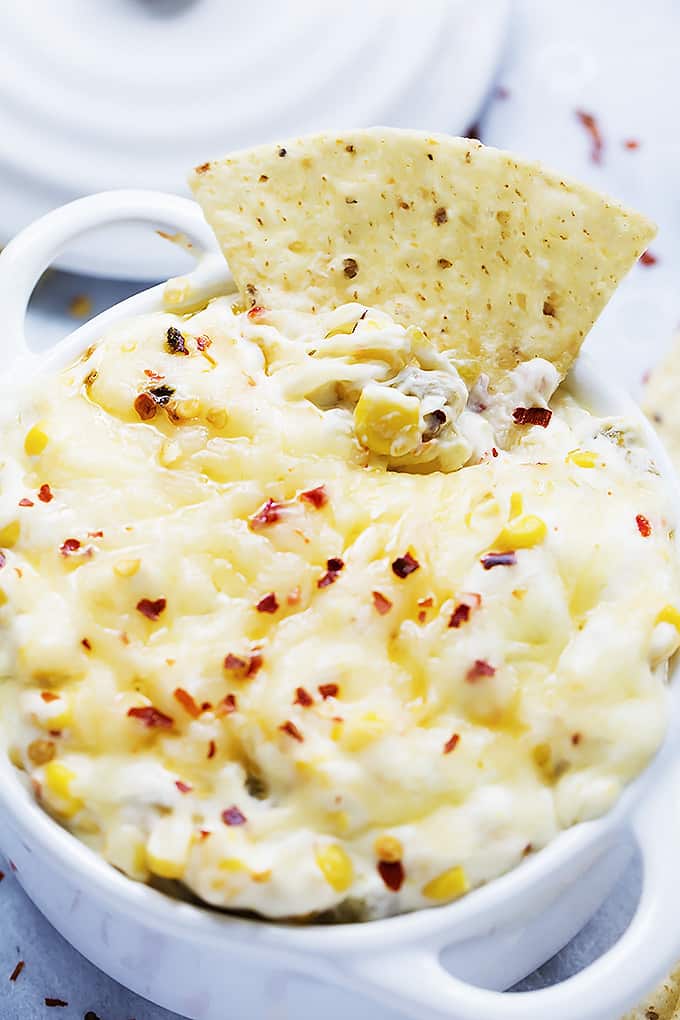 hot cheesy corn dip in a bowl with a chip dipped in it.