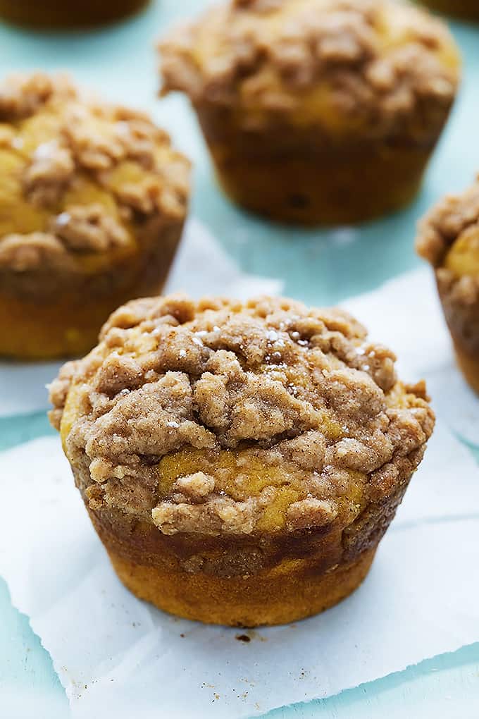 a pumpkin cream cheese streusel muffin with more muffins in the background.