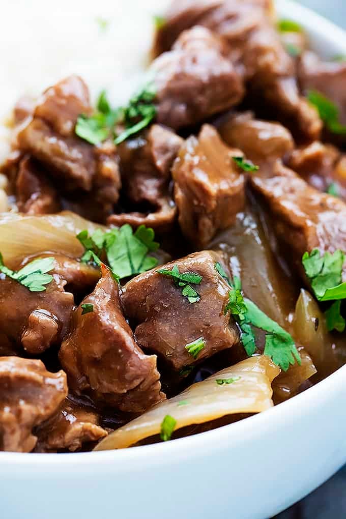 close up of slow cooker beef on rice in a bowl.