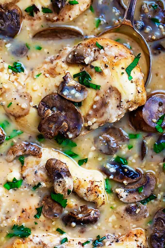 close up of slow cooker chicken marsala with a spoon lifting up a piece of chicken.