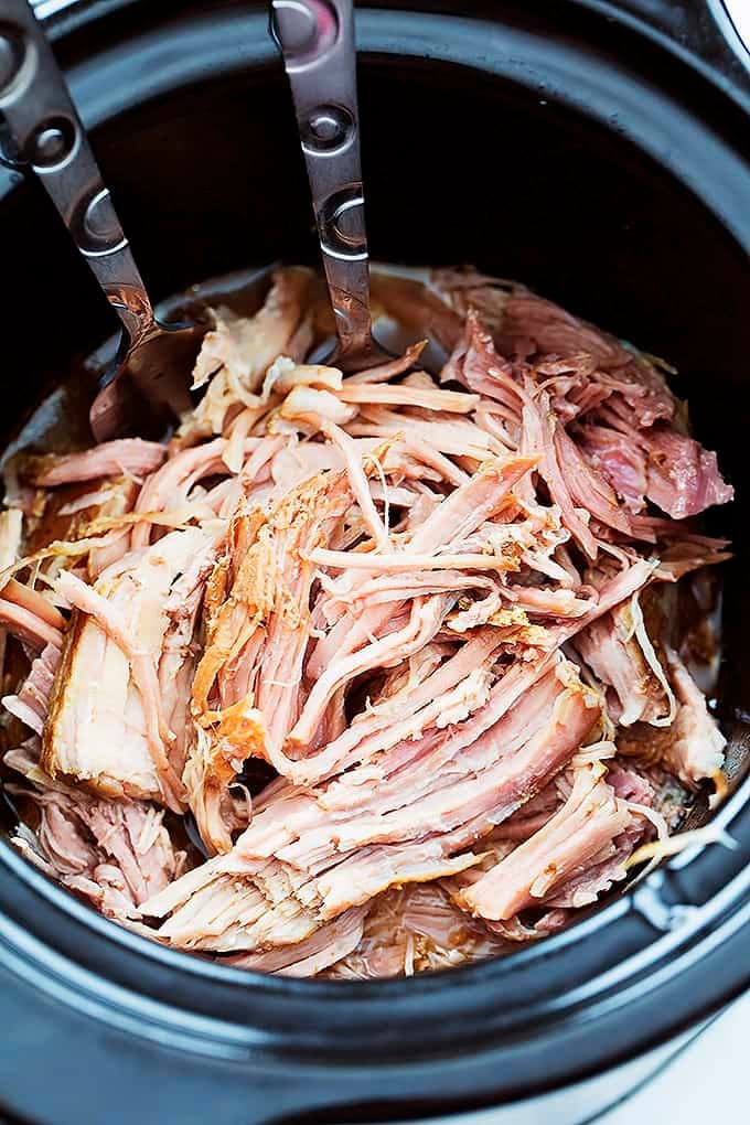 slow cooker kalua pork with serving spoons in a slow cooker.
