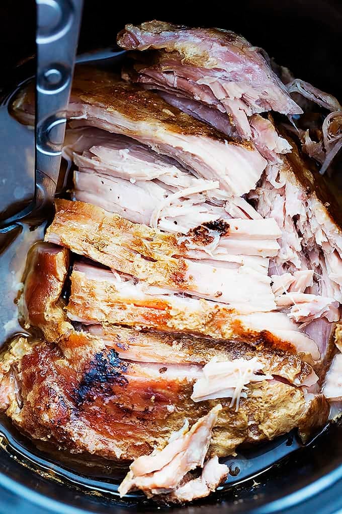 close up top view of slow cooker kalua pork with a serving spoon in a slow cooker.