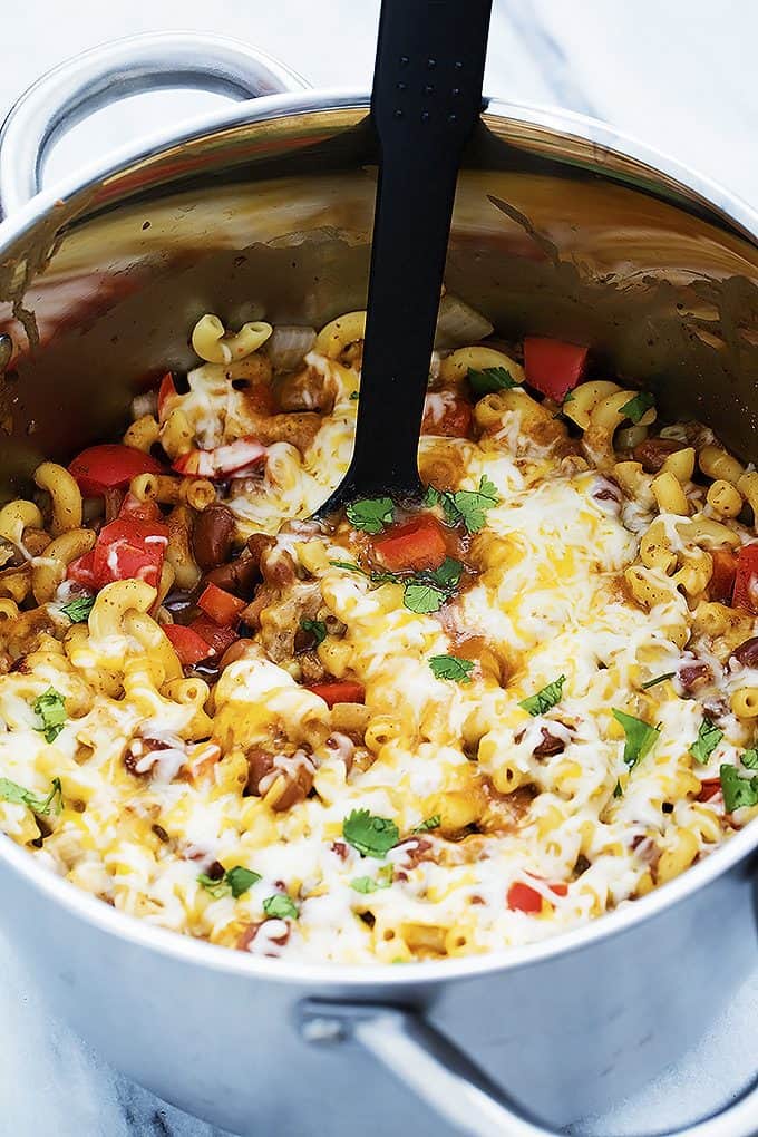 cheesy chili mac with a serving spoon in a cooking pot.