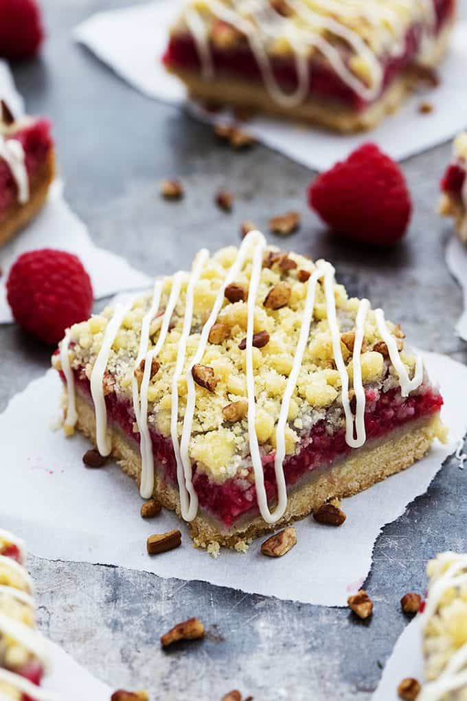 a raspberry crumb pie bar with raspberries and more bars on the side.