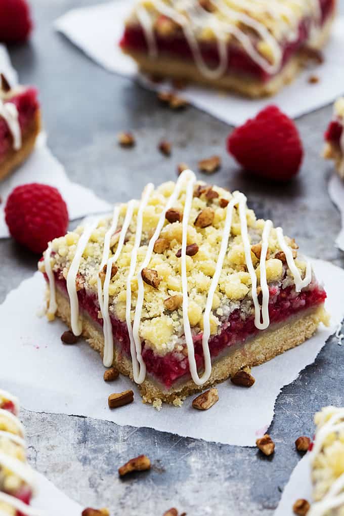 a raspberry crumb pie bar with raspberries and more bars on the side.