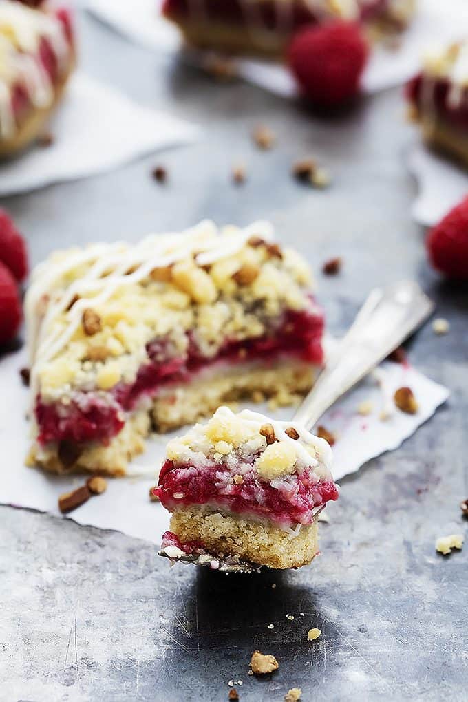 a raspberry crumb pie bar with a bite missing with the bite on a fork on the side.