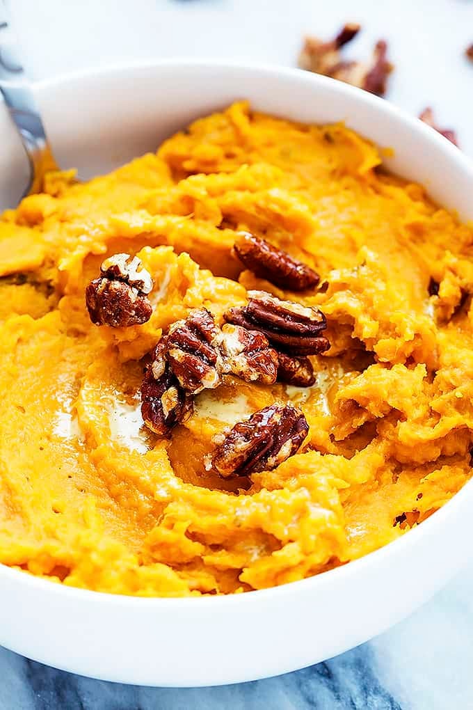 close up of slow cooker mashed sweet potatoes with a serving spoon in a bowl.