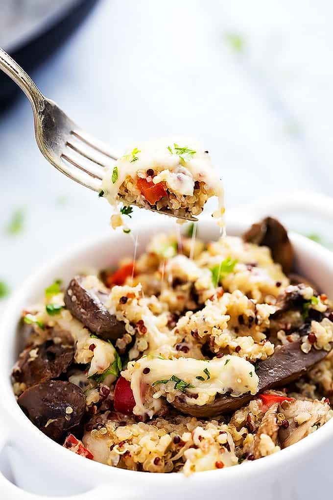 a fork lifting up a bite of slow cooker cheesy mushroom quinoa from a bowl.