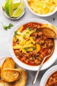 overhead view of ground beef soup with cheese and garnishes on the table