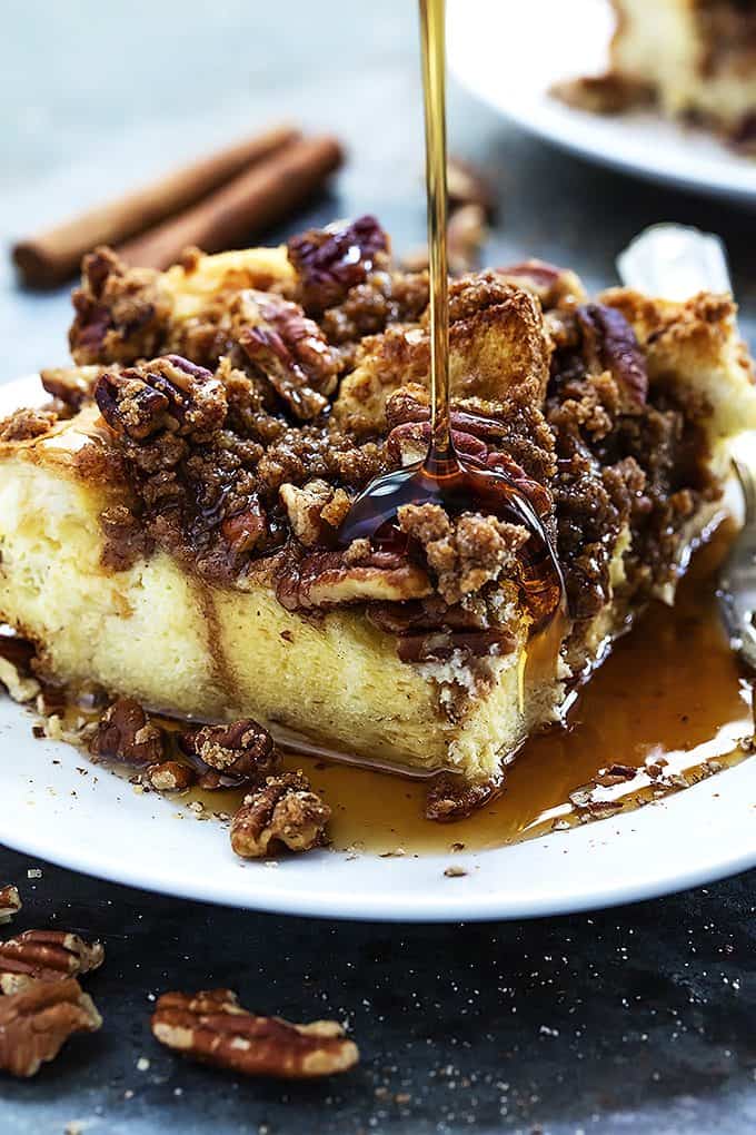 a piece of overnight cinnamon pecan French toast casserole on a plate with syrup being poured on top.