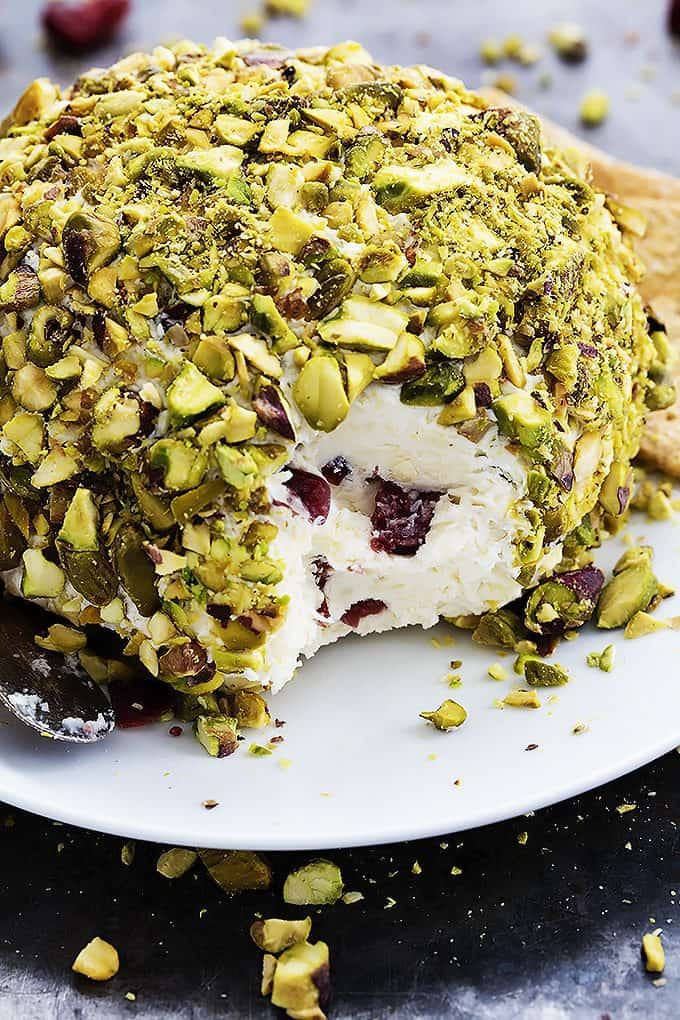 close up of cranberry pistachio cheeseball with some missing on a plate.