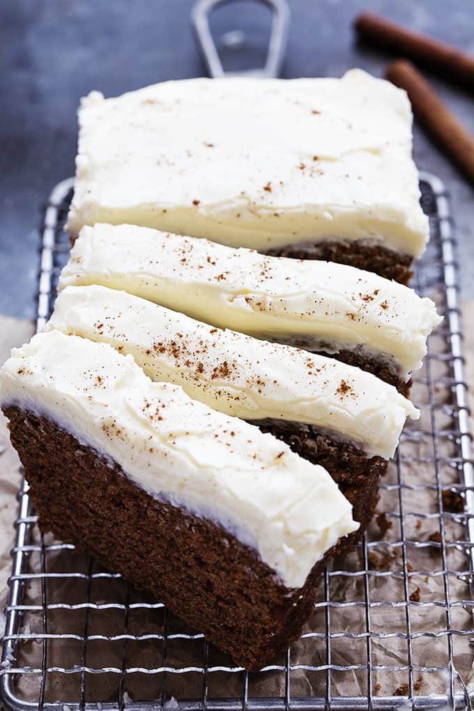 gingerbread loaf with cream cheese frosting cut into slices on a cooling rack.