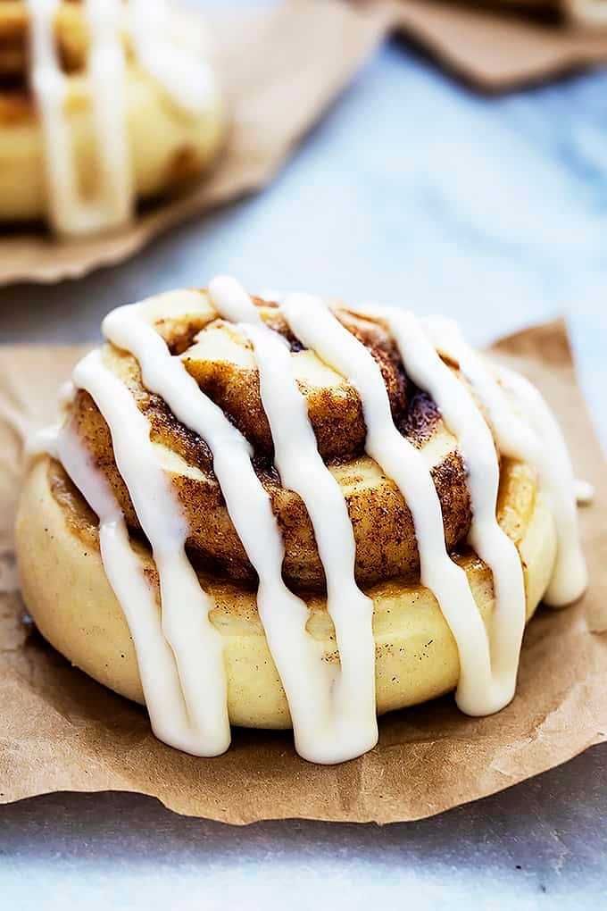 a mashed potato cinnamon roll with icing on top with more rolls in the background.