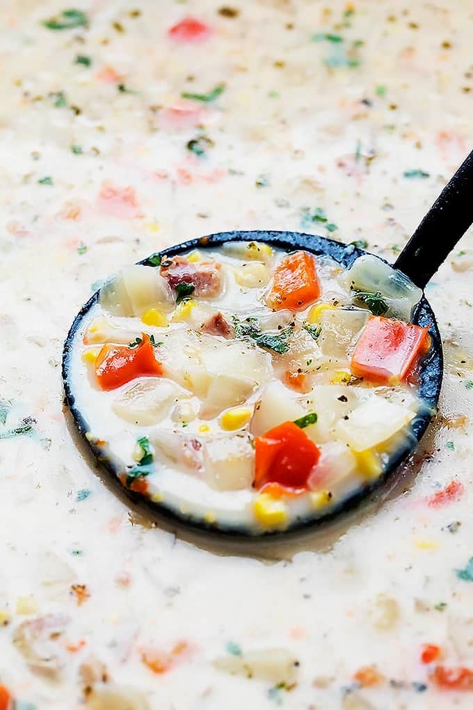 close up of a serving spoon in slow cooker potato bacon corn chowder.