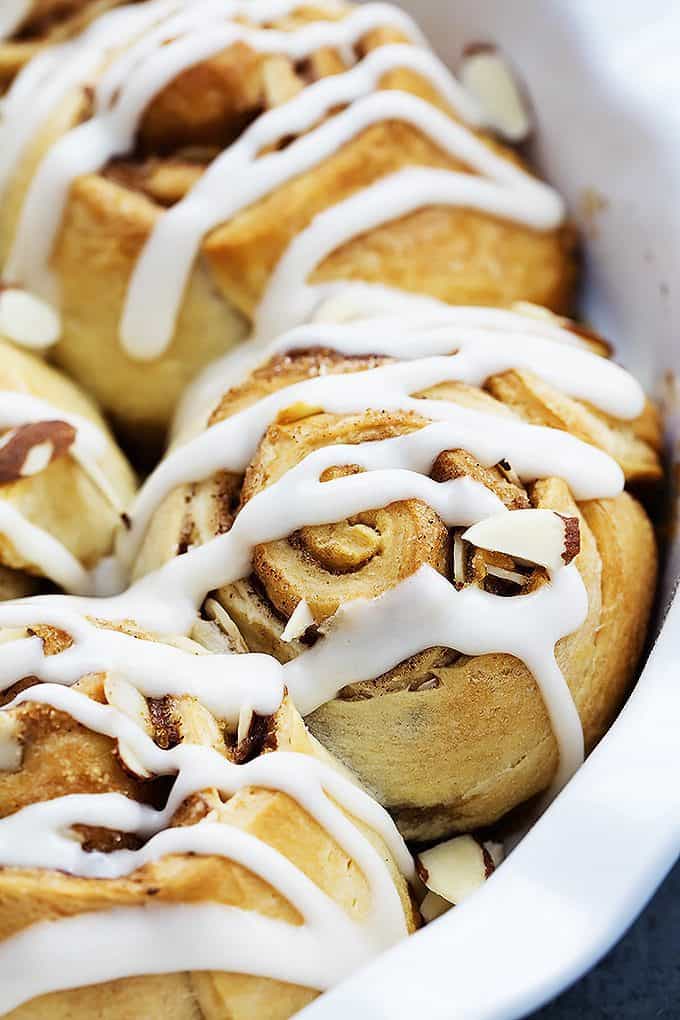 close up of flaky almond cinnamon buns in a round dish.