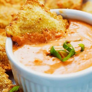 ravioli with breadcrumb coating being dipped in sauce