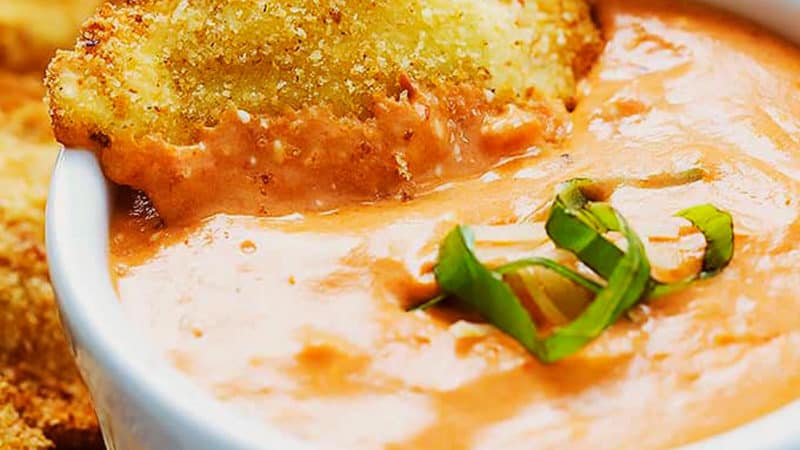 ravioli with breadcrumb coating being dipped in sauce