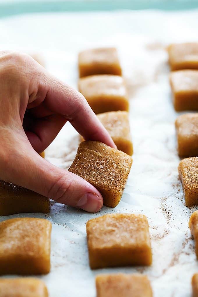 a hand picking up a vanilla cinnamon caramel with more caramels around it.